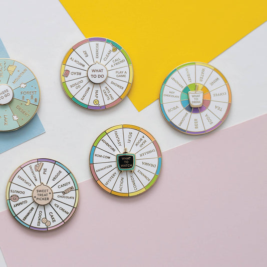 Set of four colorful spinning enamel pins labeled for snacks, drinks, and activities.