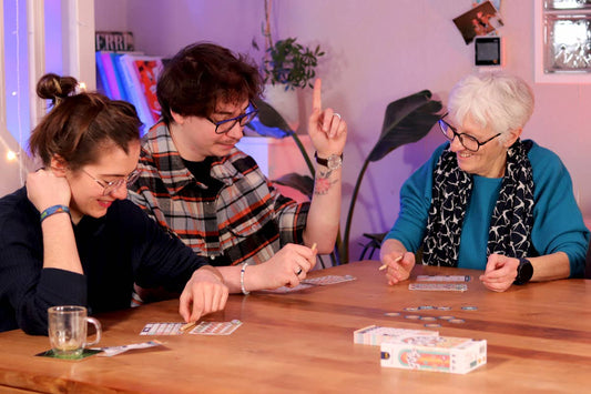Three people playing Fifty strategy board game at a wooden table.
