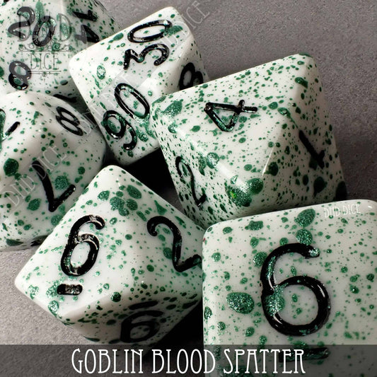 White acrylic 7-dice set, Goblin Blood Spatter (Hand Painted), with green splatter and black numbers.