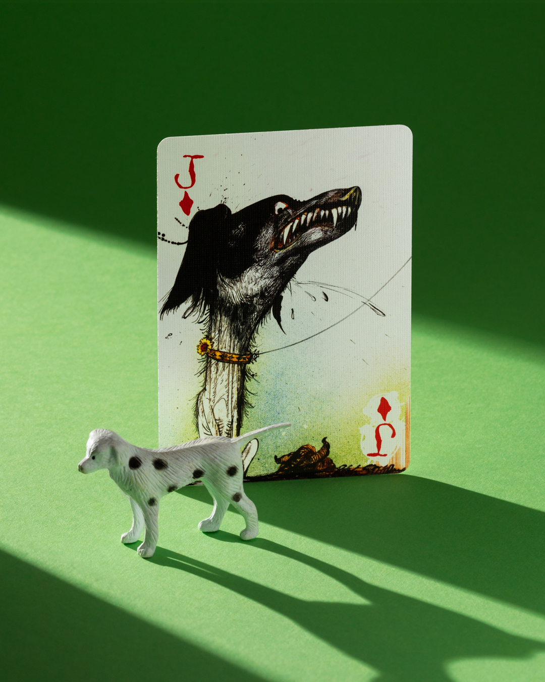 Jack of Diamonds from Flying Dog Edition 2 playing cards, positioned behind a small spotted dog figurine.