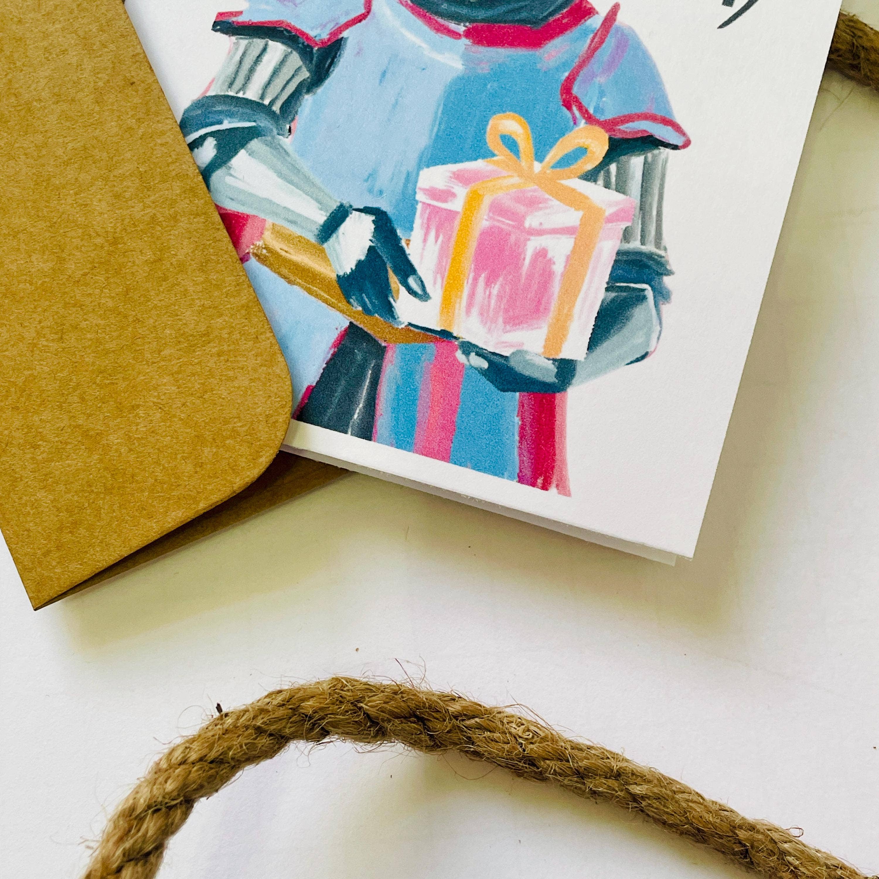 Medieval & Renaissance Role-Playing Birthday Card with gift, kraft envelope, and rope on white surface.