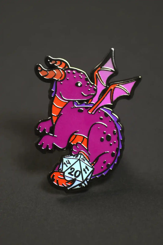 Purple dragon with pink wings and orange horns holding a D20, enamel pin from Pin: Cute Pin Pack collection.