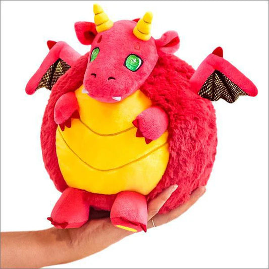 Squishable Red Dragon 15 plush with yellow horns, yellow belly, and small black wings held in a hand.