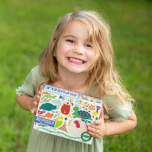 Petite Pets 20 Piece Puzzle box held by a child in a green dress sitting on grass.