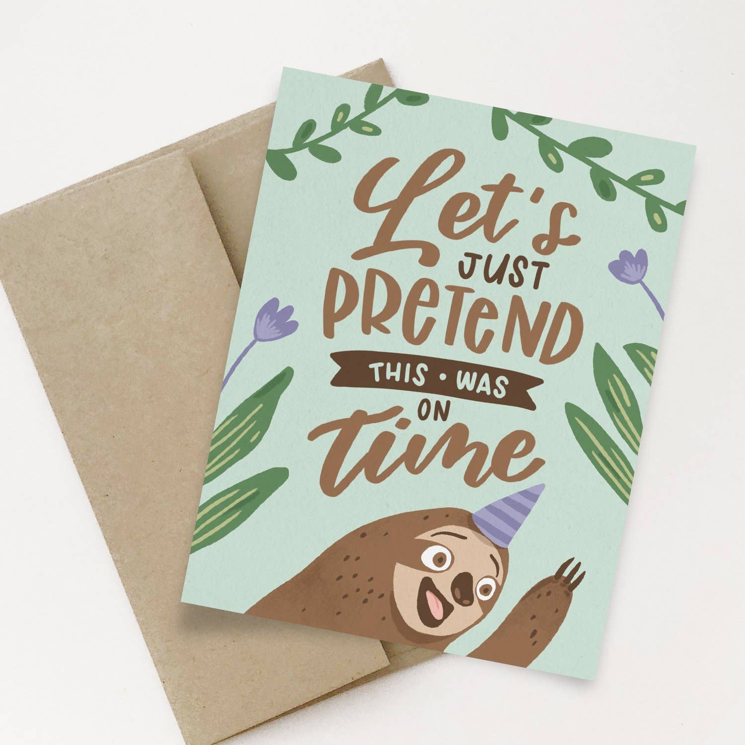 Let’s Just Pretend Sloth card with smiling sloth in party hat, blank inside, includes kraft envelope.