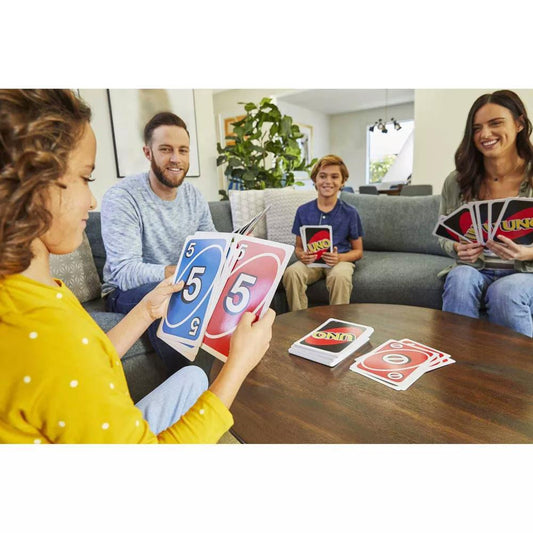Giant Uno card game with four people playing using large, colorful cards at a table.