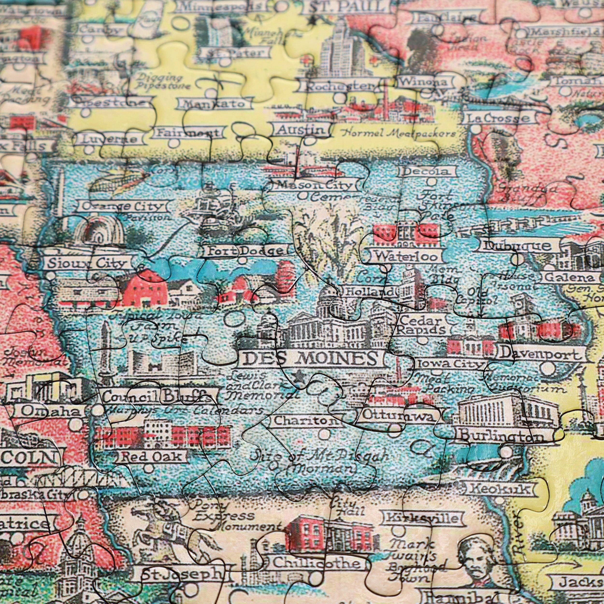 America the Wonderland 1,000-piece jigsaw puzzle featuring a colorful illustrated map of Iowa with cities, rivers, and landmarks.