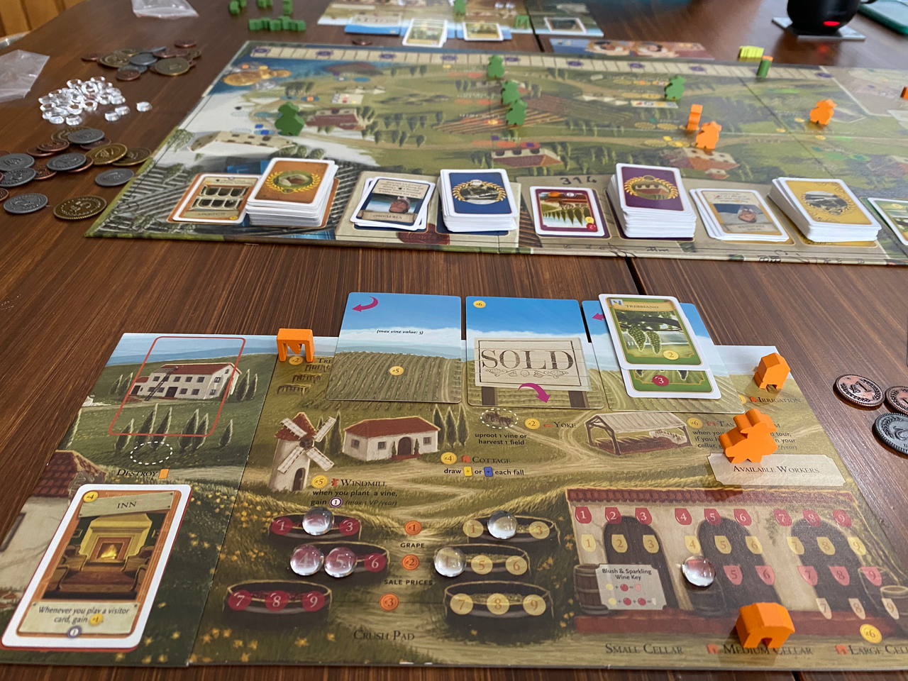 Tuscany Essential Edition Viticulture Expansion components with cards, pieces, and coins on a wooden table.