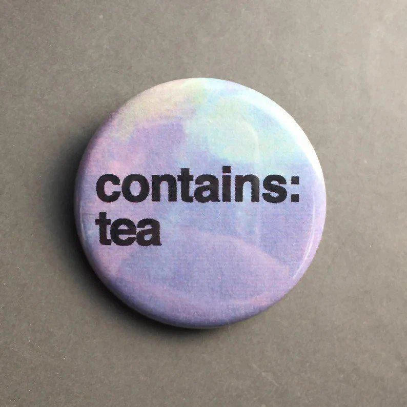Contains Tea button pin, 1.25 round, purple-blue gradient background with bold black tea text.