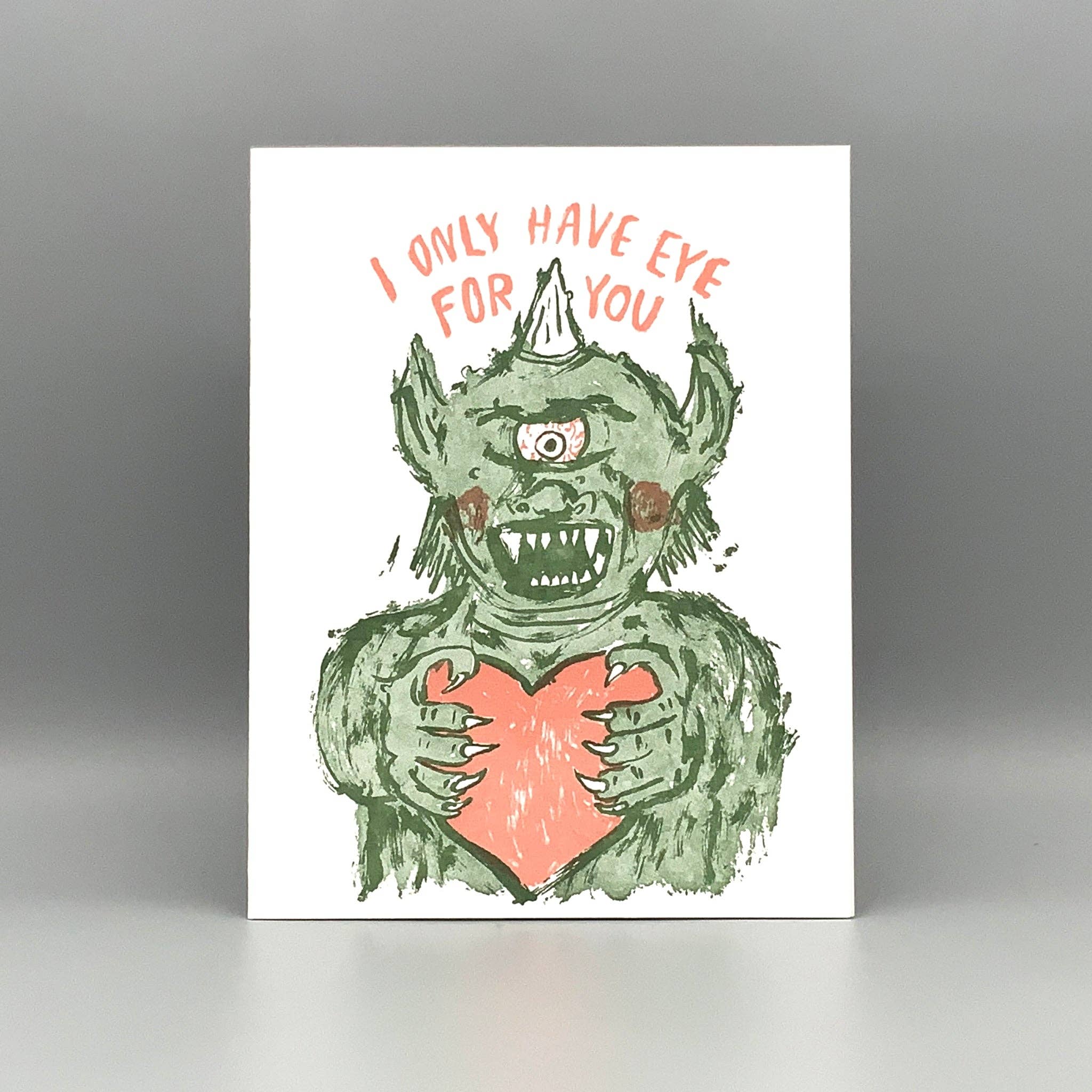 Eye For You letterpress card with a green one-eyed monster holding a pink heart and the phrase above.