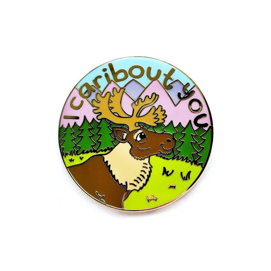 Kolorspun Pins I Caribout You round enamel pin featuring a cartoon caribou, trees, pastel sky, and text.