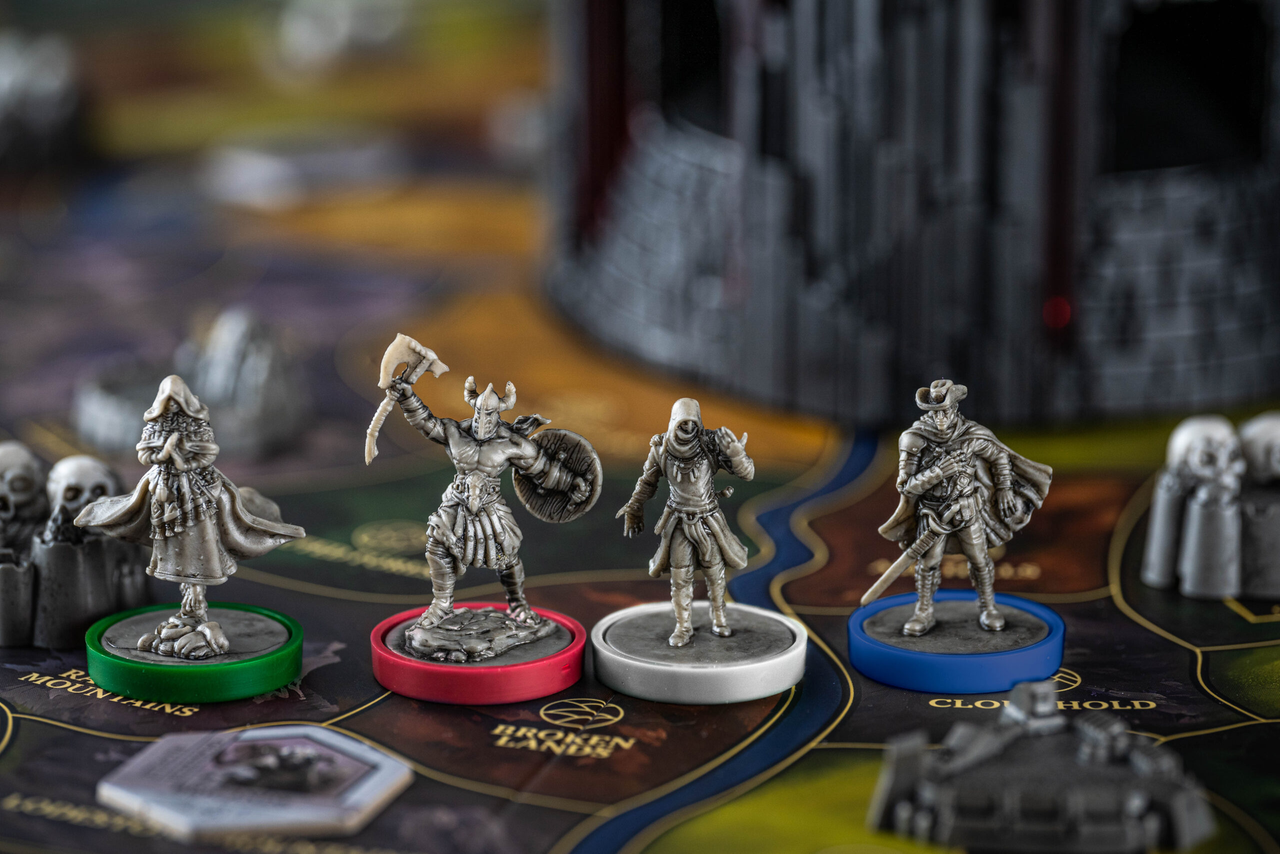 Return to Dark Tower miniatures on colored bases displayed in front of the game tower on the board.