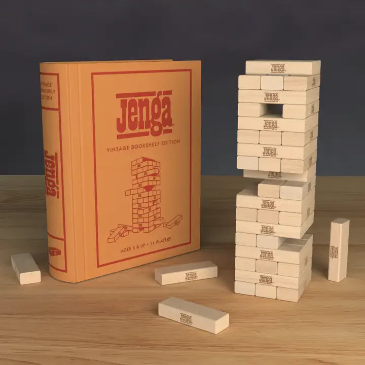 Jenga Vintage Bookshelf Edition blocks stacked beside the book-shaped box on a wooden table.