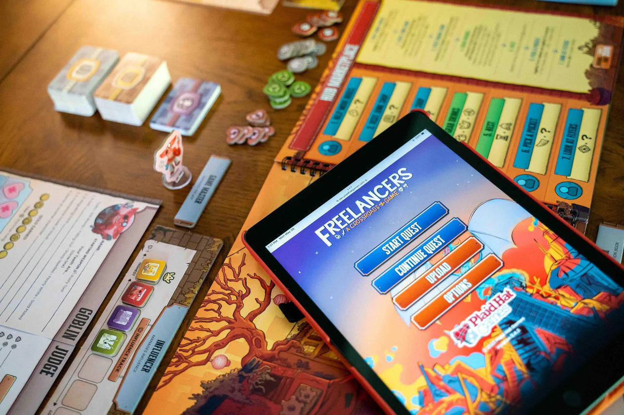 Tablet with Freelancers: A Crossroads Game app, surrounded by board game pieces and cards.