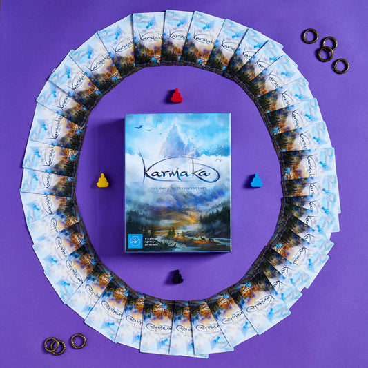 Karmaka card game box with cards, four colored tokens, and gold rings.