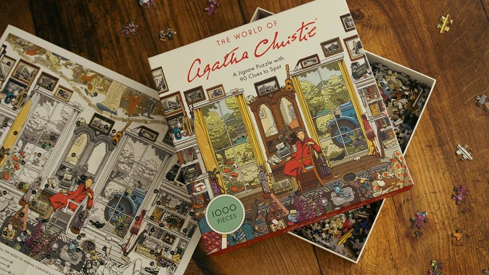 World of Agatha Christie 1000 Piece Puzzle box open on table with puzzle pieces in progress.
