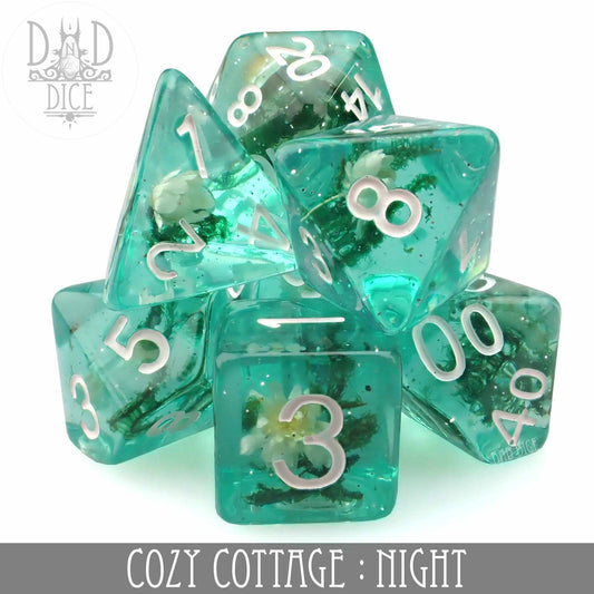Cozy Cottage Night teal 7-piece dice set with white numbers and small plants inside.