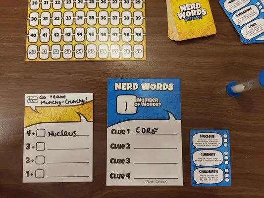 Nerd Words: Science board game components, including clue cards, score sheet, and pieces arranged on a wooden surface.