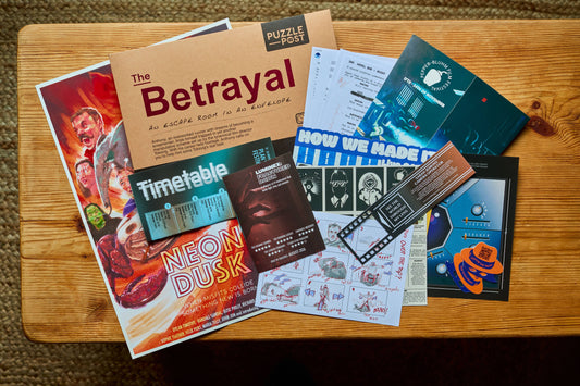 The Betrayal Escape Room Puzzle Board Game materials and colorful flyers spread out on a tabletop.