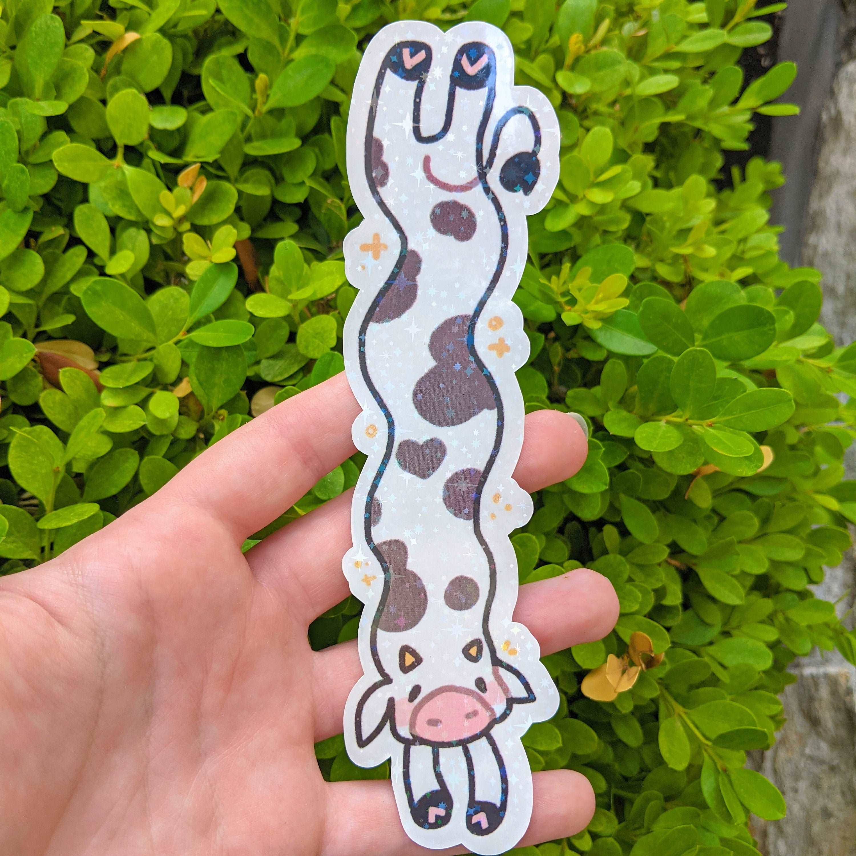 MORE Sparkly Long Cow Sticker with brown spots, waterproof, held in a hand.