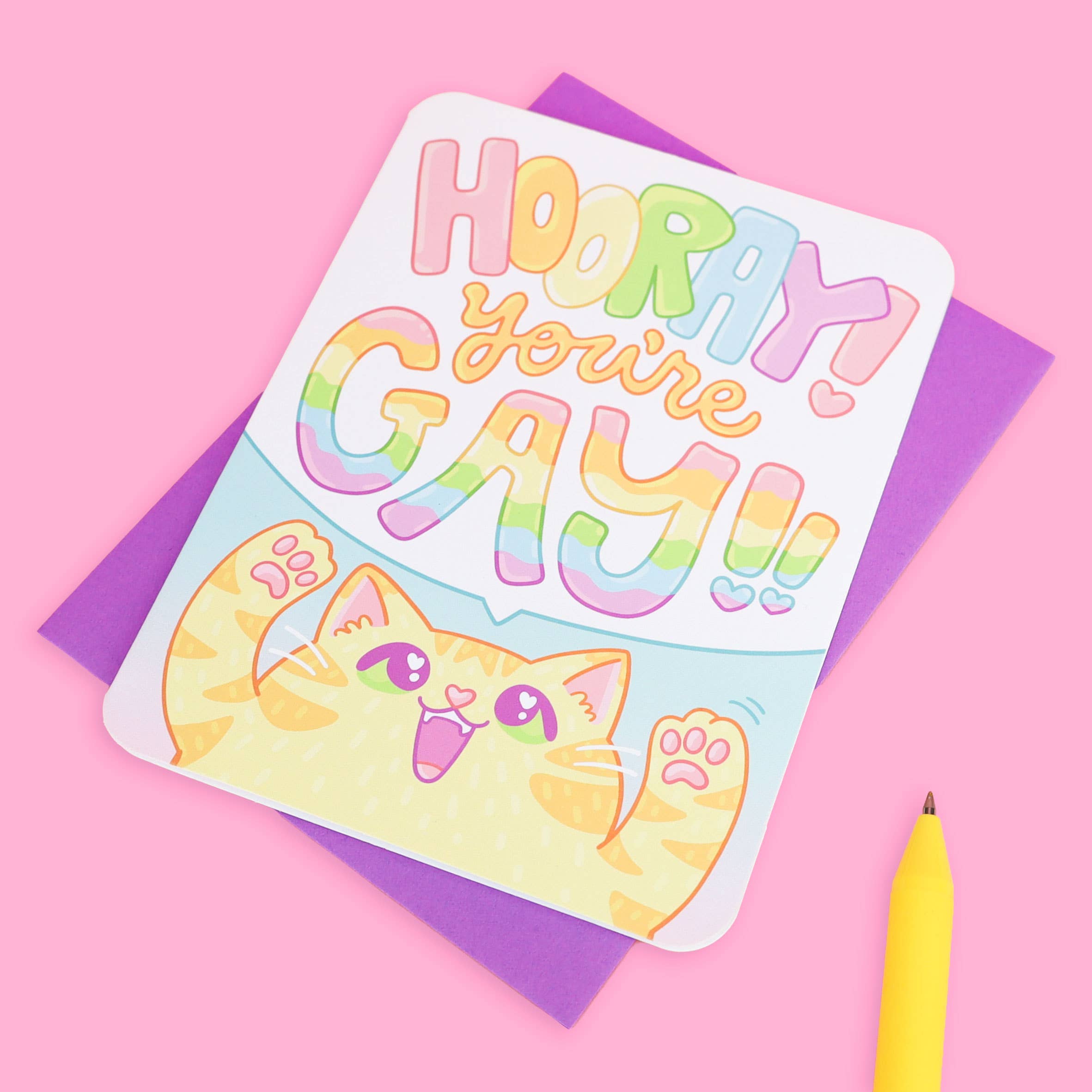 Hooray You’re Gay LGBTQ Kitten card on recycled paper with purple envelope and yellow pen.