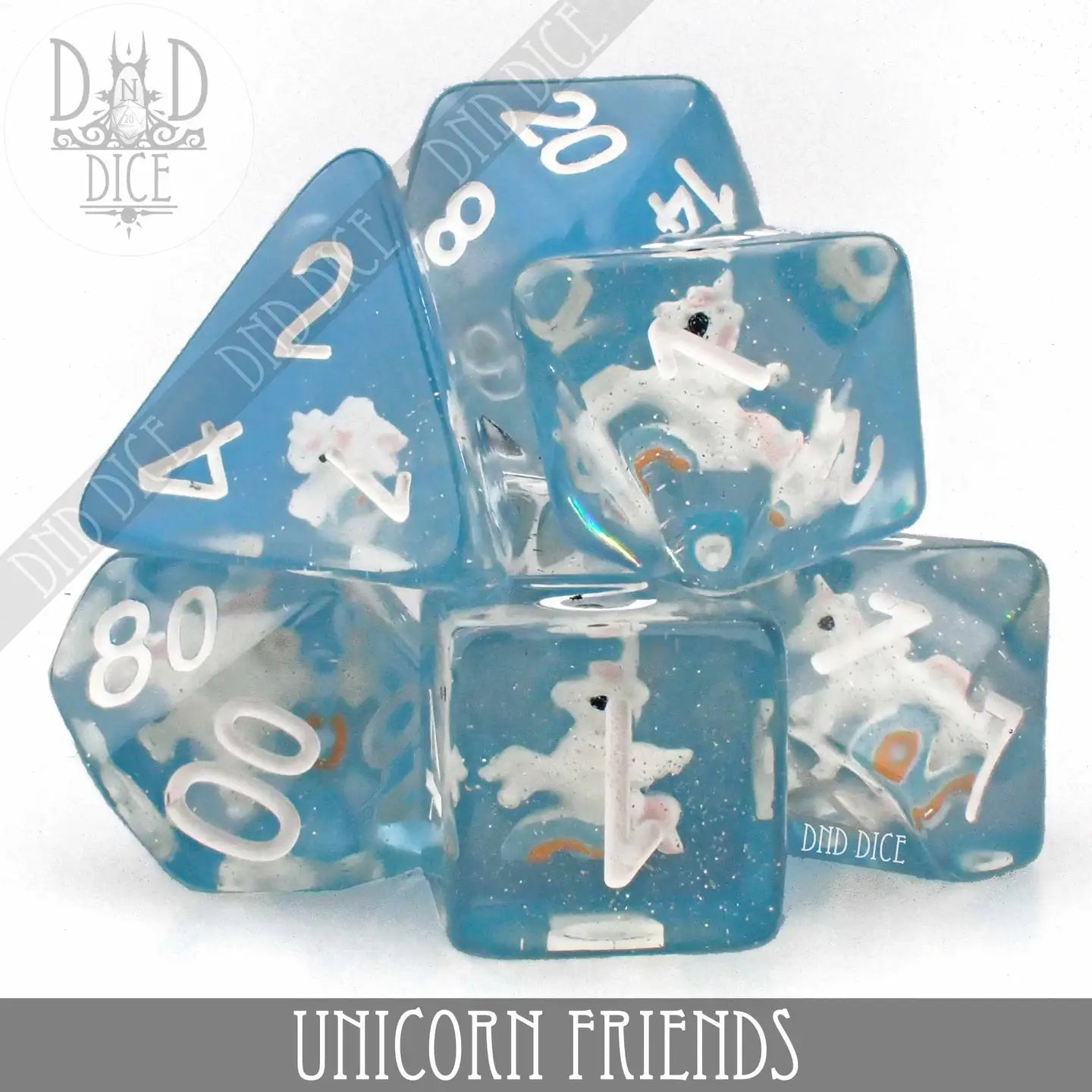 7-piece blue polyhedral dice set with white numbers and tiny unicorn figures inside.