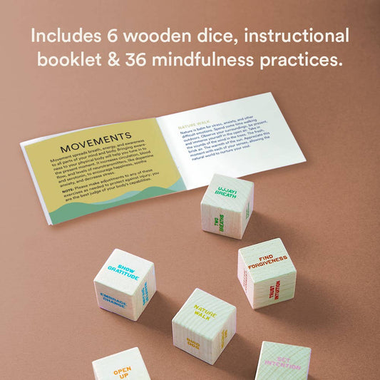 Six wooden Mindfulness Dice with meditation exercises and an open booklet displayed on a brown table.