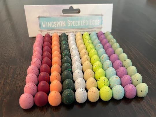 Wingspan: Speckled Eggs tokens in various shades with product label in background.