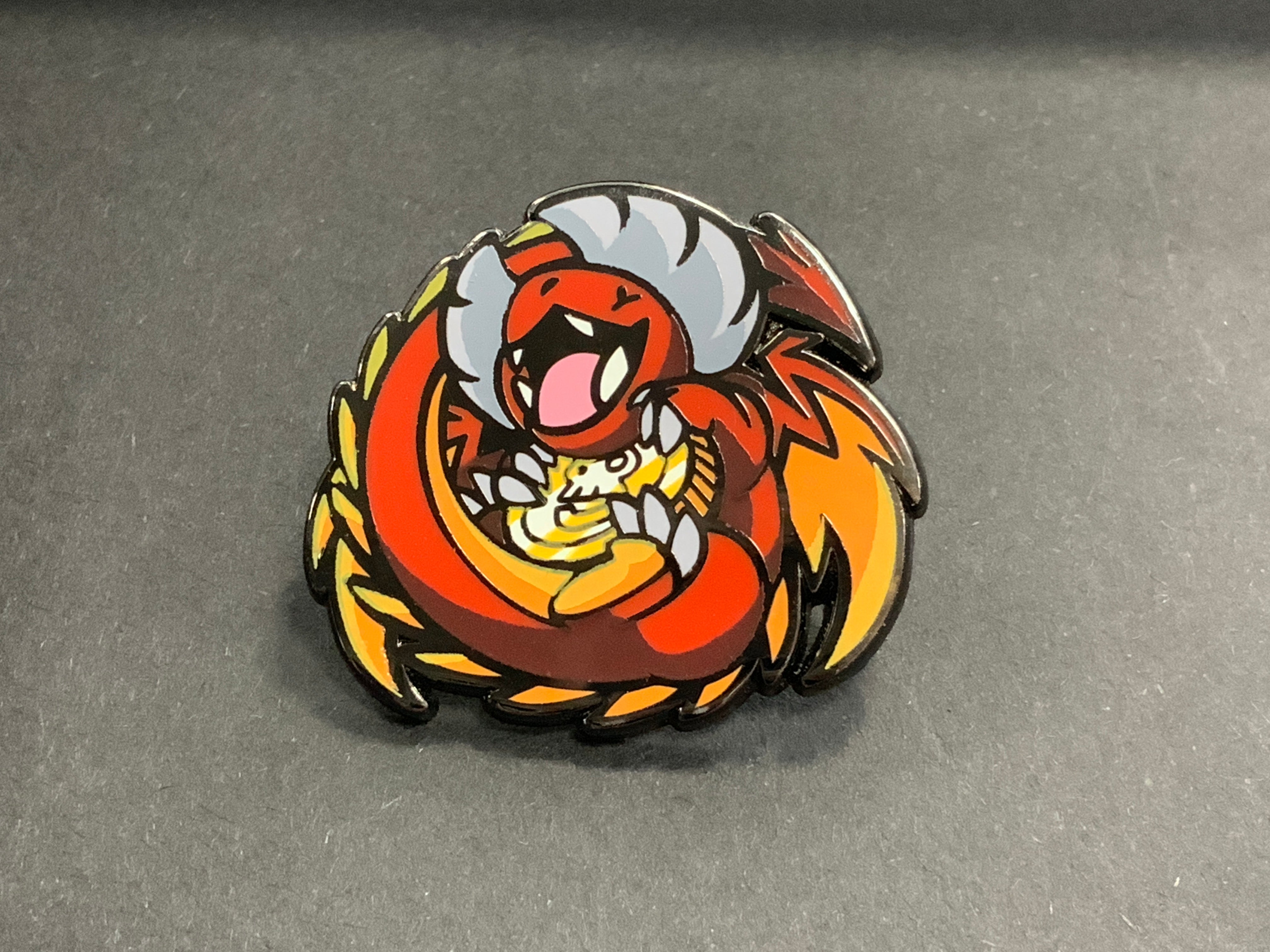 Heliana Monster Hunting Pin Dragonling with a red and yellow dragon curled around a golden egg.
