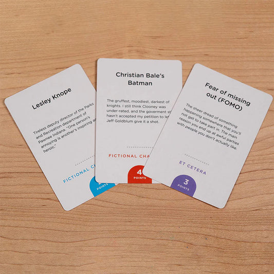 Three Monikers: Serious Nonsense expansion cards with unique text and colored point values in circles.