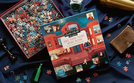 World of Agatha Christie: And Then There Were None puzzle, book, and green bottle on blue cloth, partly assembled.