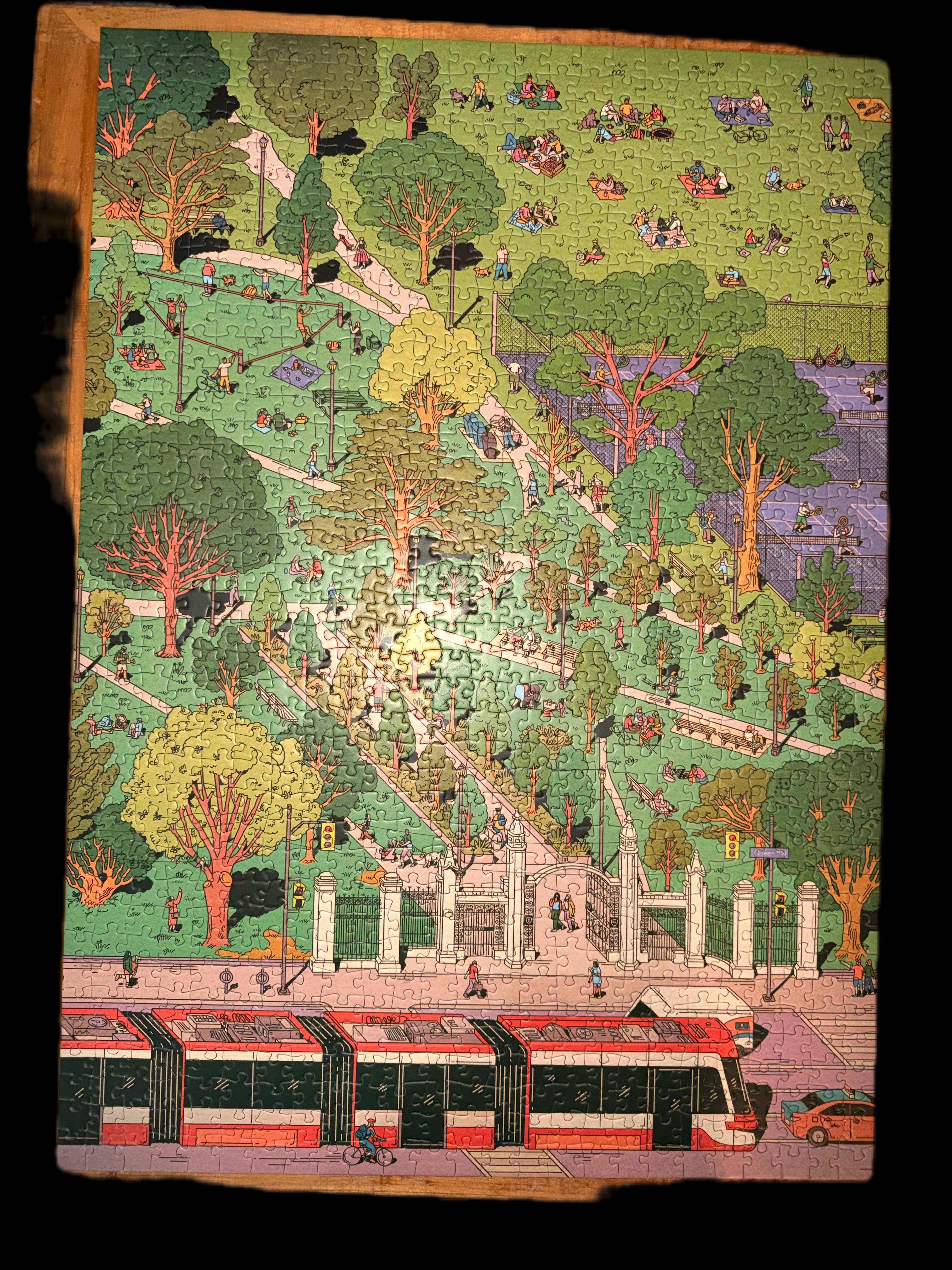 Trinity Bellwoods 1000-piece puzzle with Kathleen Fu’s illustration of a park, people, trees, pond, and streetcar.