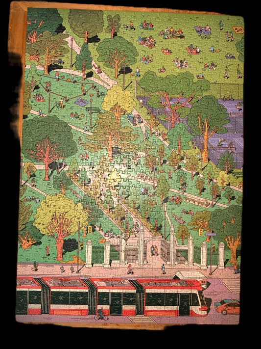 Trinity Bellwoods 1000-piece puzzle with Kathleen Fu’s illustration of a park, people, trees, pond, and streetcar.