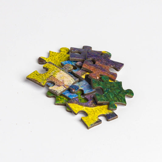 Puzzle - Georges Seurat - Sunday Afternoon jigsaw pieces spread on a white background.