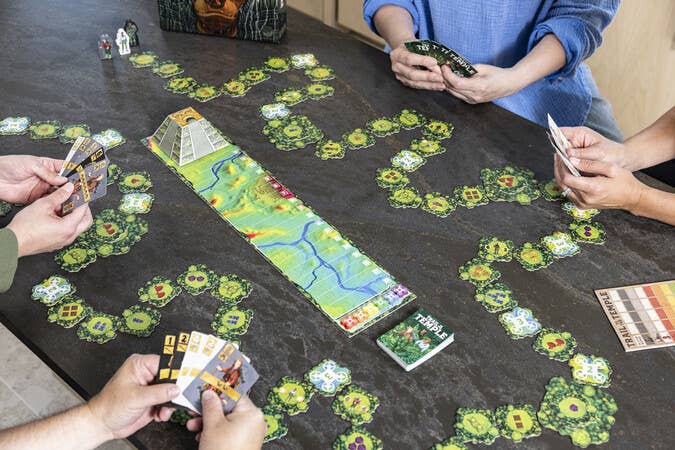 Trail To The Temple board game with hex tiles, cards, and pyramid figurine at the center for four players.