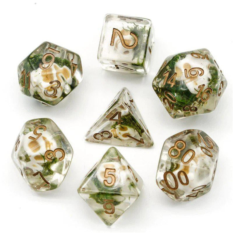 Clear Skull Dice Set of seven clear polyhedral dice with gold numbers and green-white inclusions for D&D.