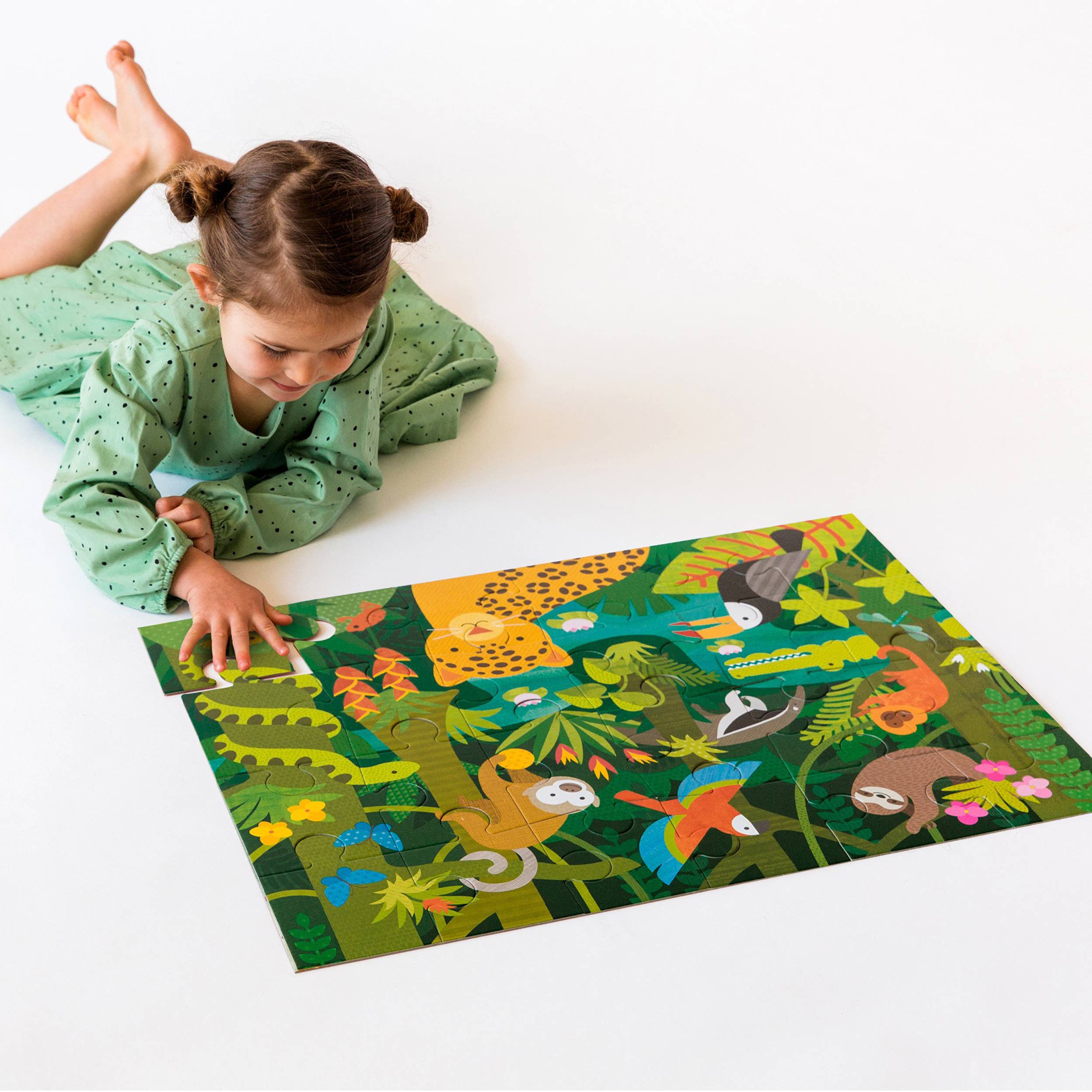 Wild Rainforest 24-Piece Floor Puzzle being assembled on a white surface by a young girl in a green dress.