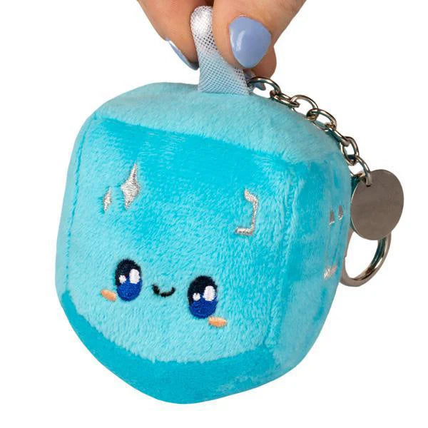 Micro Dreidel plush blue keychain with embroidered smile and shiny accents held in a hand.