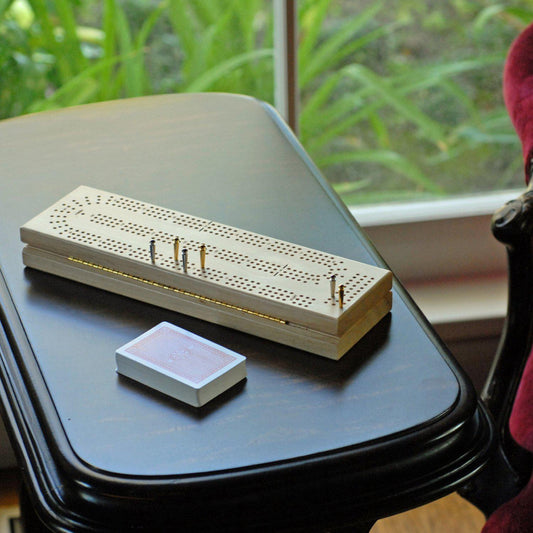 Cribbage travel set with metal pegs and cards on a black table.