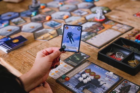Scythe Expeditions Ironclad edition board game with tokens, tiles, and a card held by a person.