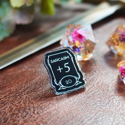 Sarcasm +5 Stat acrylic pin featuring a dice and sword design.