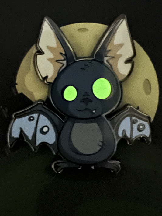 Zombat Bat Enamel Pin featuring a glow-in-the-dark cartoon bat with green eyes, large ears, and a yellow full moon.