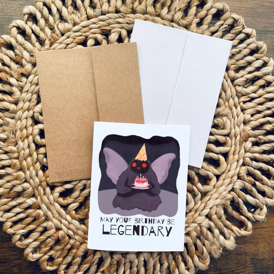 Mothman Cryptid birthday card featuring Mothman in a hat with cake and the text May your birthday be legendary.