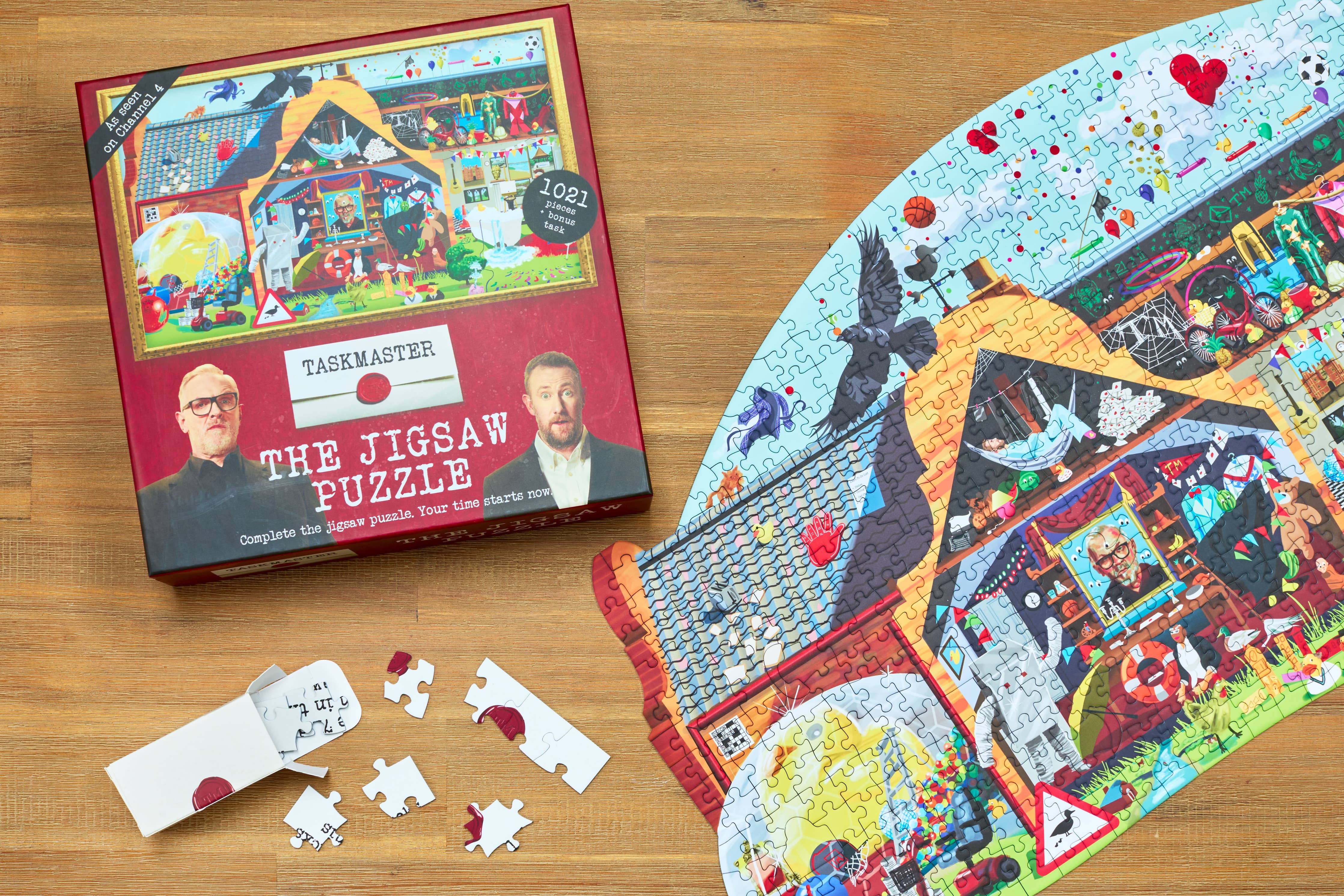 Taskmaster Jigsaw Puzzle (1021 pieces, Secret Task) with some loose pieces on a wooden table.