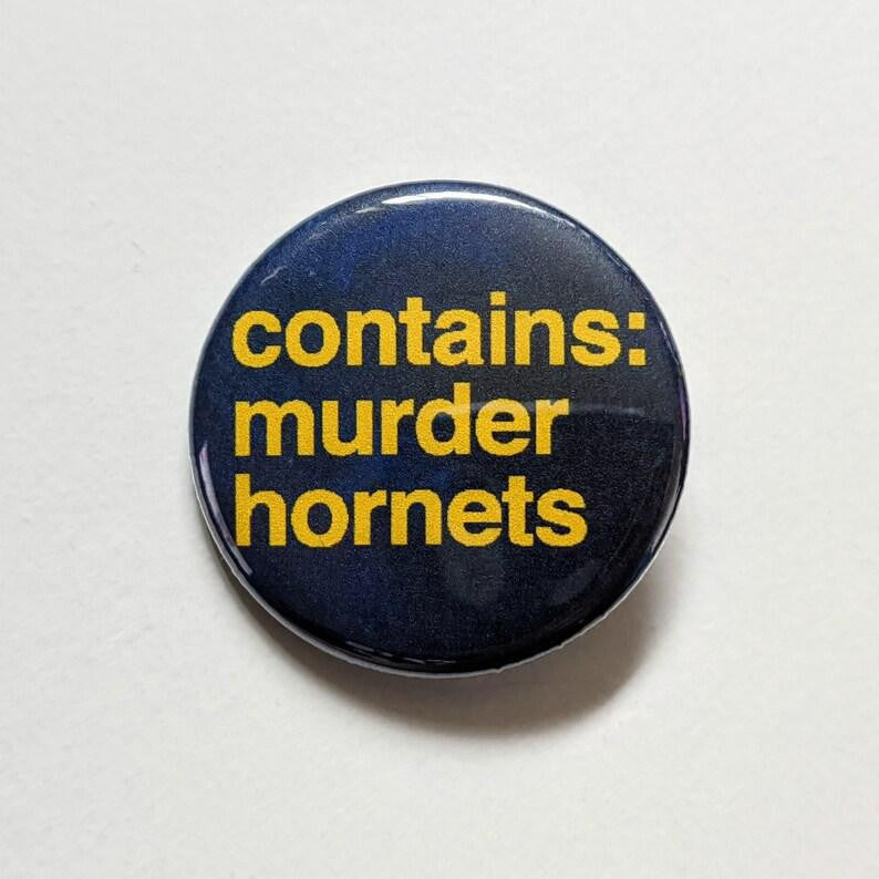 Contains Murder Hornets button pin, 1.25 inches, yellow text on dark background.