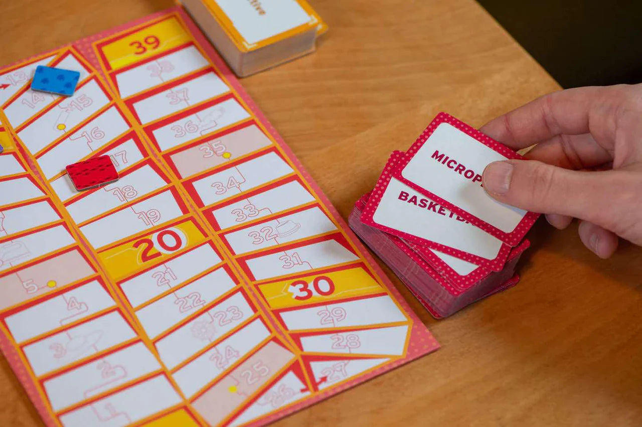 Mind Map board game with numbered spaces, playing pieces, and a hand holding cards on a wooden table.