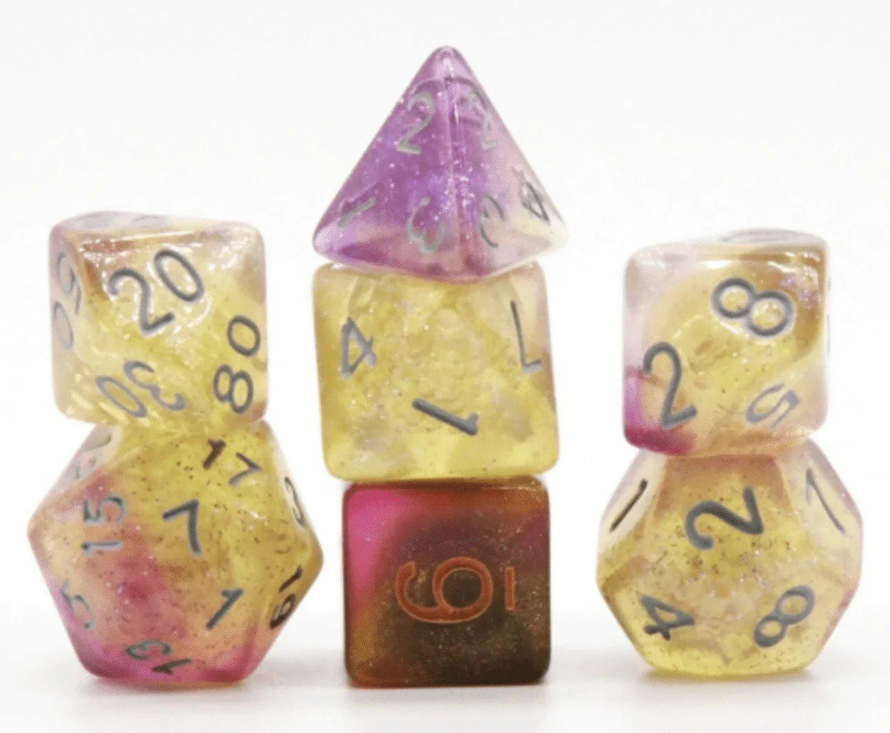 Dream Nebula RPG Dice in three stacks: yellow, pink, and purple with glitter and large numbers.