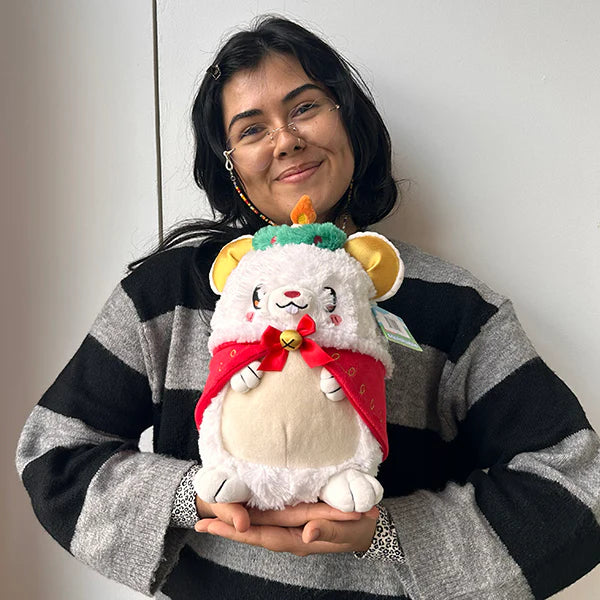 Person wearing glasses holds a Festive Mouse Mini Squishable plush with a red cape and green hat.