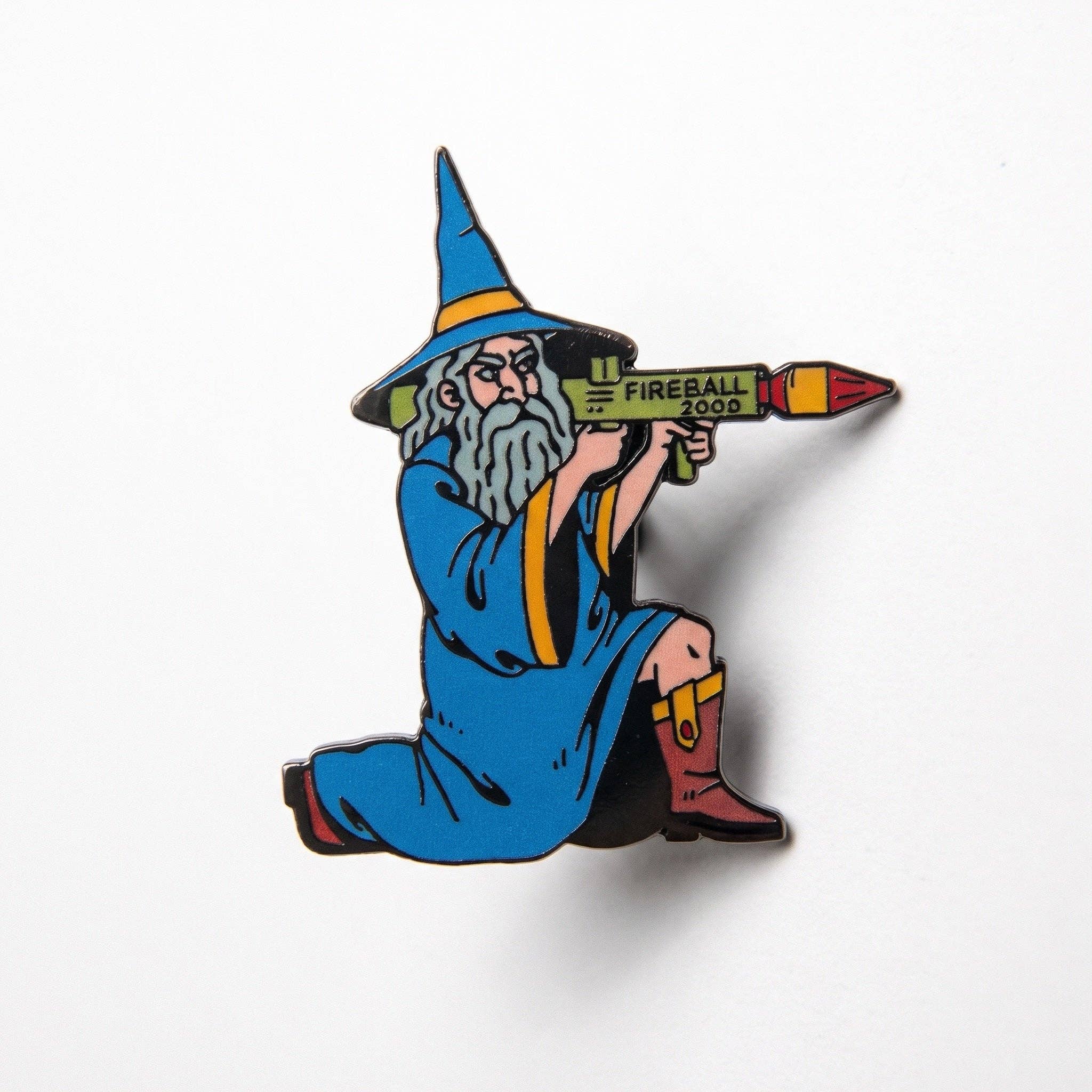 Fireball Wizard enamel pin featuring a wizard in a blue robe firing a black metal rocket launcher labeled FIREBALL 2000.