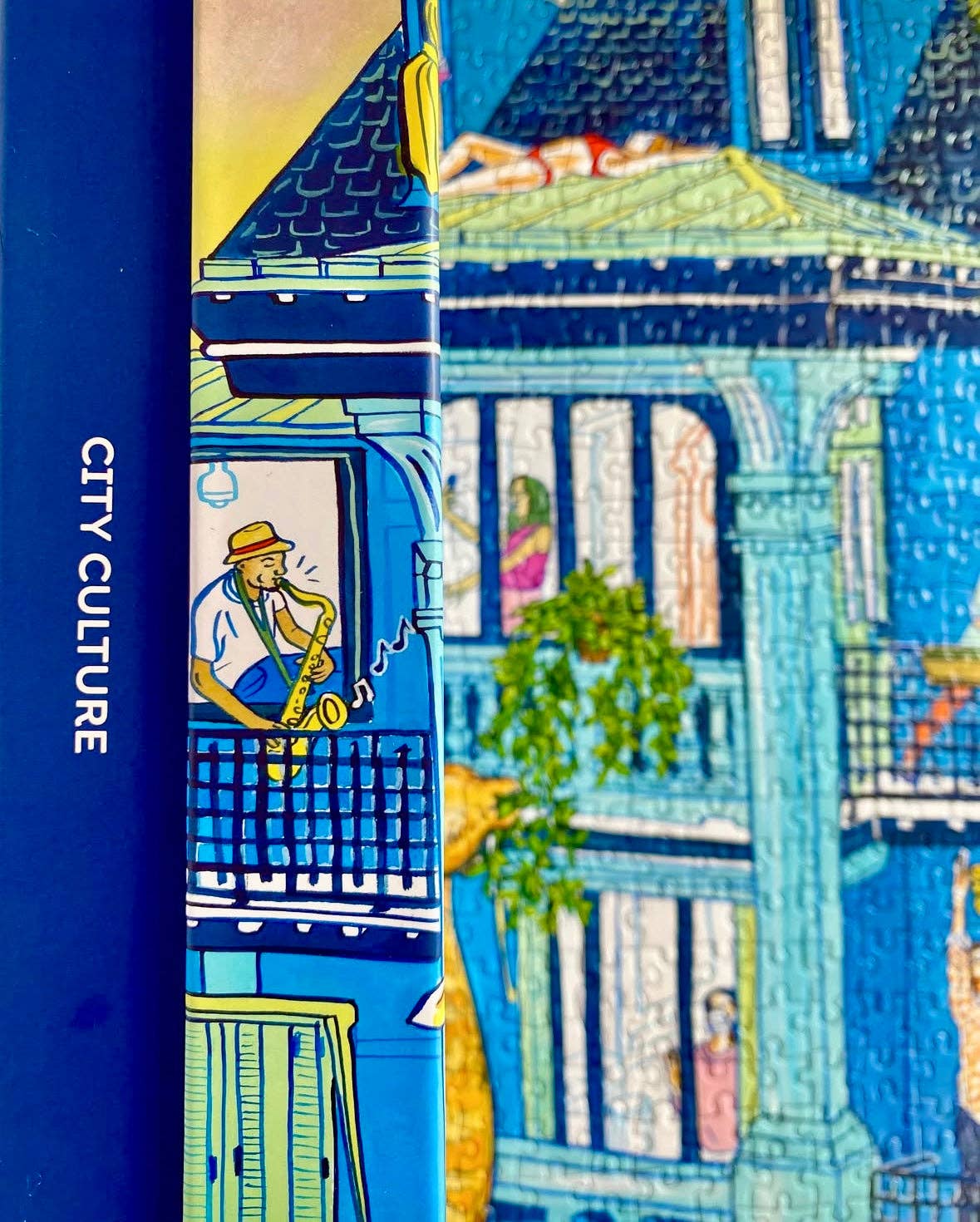 City Culture 1000-piece puzzle with Jules Monson’s art of a man playing saxophone on a colorful balcony.